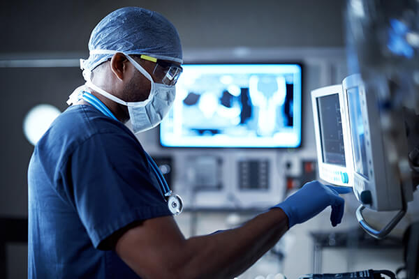 Surgeon uses a variety of digital electronics to monitor a patient in an operating room.