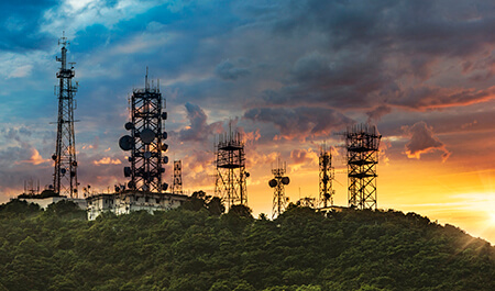 Silhouette of antenna towers and repeaters of communication and telecommunication on a mountain at sunset.