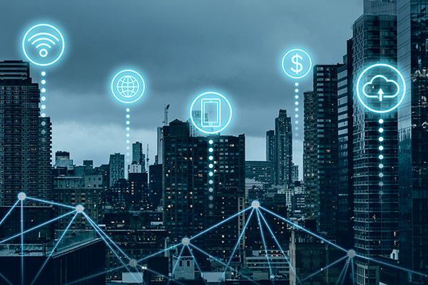 Blue gray city skyline with IoT icons representing wifi, the internet, a computer, finance & cloud storage